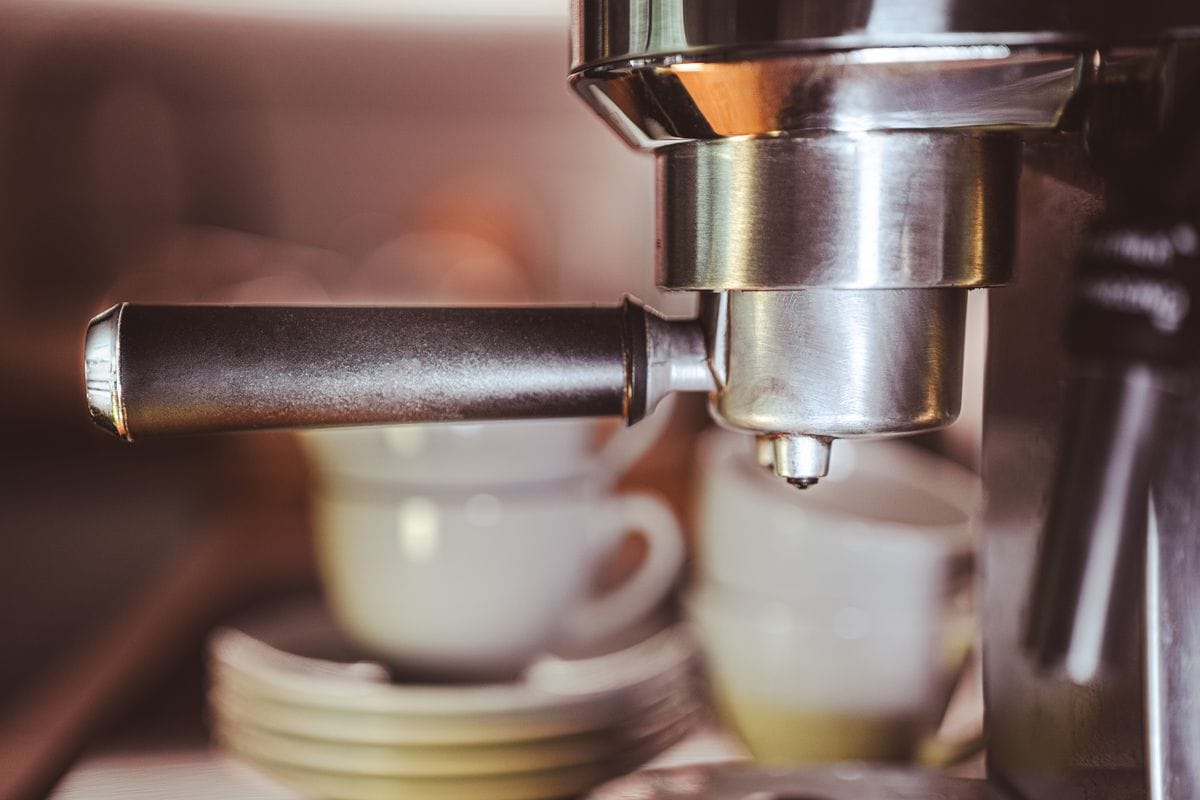 Espresso machine group head pulling espresso into white cups