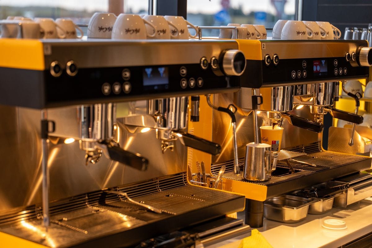 Two commercial espresso machines on a warm-lit cafe bar